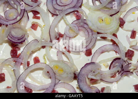 Preparing an Alsatian dish,  tarte flambée, with sour cream, ham, lardons and red onions Stock Photo