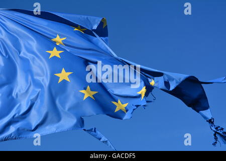 The european union twelve star flag torn and with knots in the wind on blue sky Stock Photo