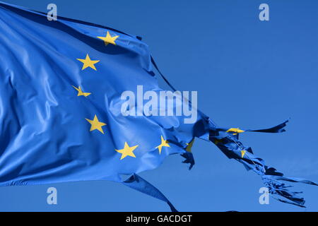 The european union twelve star flag torn and with knots in the wind on blue sky Stock Photo