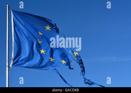 The european union twelve star flag torn and with knots in the wind on blue sky Stock Photo