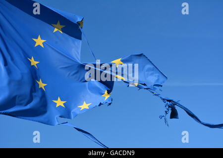 The european union twelve star flag torn and with knots in the wind on blue sky Stock Photo