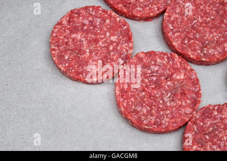 Raw red meat burgers for hamburgers of minced ground beef or pork on white parchment paper ready for cooking Stock Photo