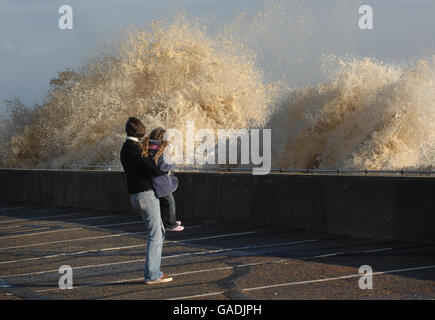 A young girl and her mother watch the waves crash against sea defences at Southwold in Suffolk today when the east coast was hit by some of the highest seas since 1953. Stock Photo