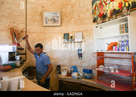 A man making coffee at Dar Ayed in Tamezret, Tunisia. Dar Ayed is a tourist point that offers a panoramic view of Tamezret. Stock Photo