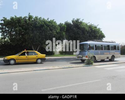 A taxi and a bus driving on the road passing by Port El Kantaoui, the tourist complex near Sousse, Tunisia. Stock Photo