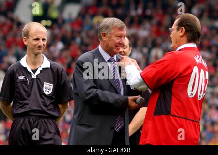 Referee Mike Riley (l) looks on on Manchester United Manager Alex Ferguson (c) is given a UNICEF badge by Goodwill Ambassador Roger Moore CBE (r) Stock Photo