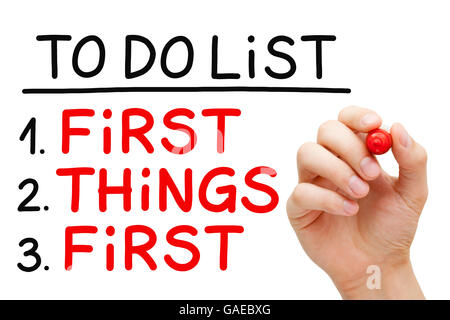 Hand writing First Things First in To Do List with red marker isolated on white. Stock Photo