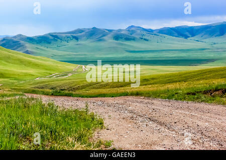 Winding dirt track through lush rolling hills of central Mongolian steppe Stock Photo