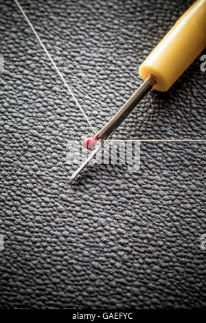 A stitch ripper about to cut through some thread Stock Photo