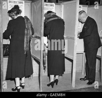 Pictured marking their ballots in voting booths are, from left to right, Mrs. Harry S. (Bess) Truman, daughter Margaret Truman and President Harry S. Truman. Stock Photo