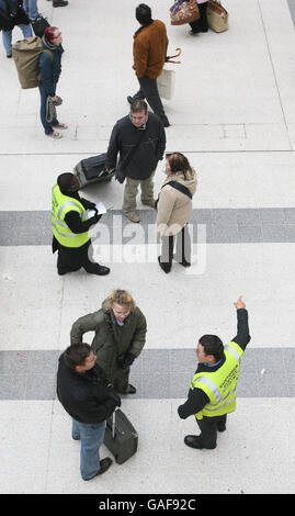 Customer service staff at a near-deserted Liverpool Street Station in London advise would-be rail passengers as thousands of them were today hit by overruns of major engineering work that closed the busy London station. Stock Photo