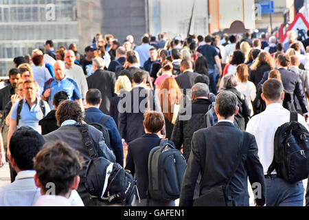 Commuter & office workers walking across London Bridge towards London Bridge train station during commuters evening rush hour to get home England UK Stock Photo