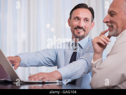 Positive smiling colleagues sitting at the table Stock Photo