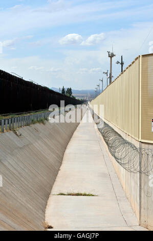 A culvert runs along the international border wall between Agua Prieta, Sonora, Mexico, and Douglas Arizona, USA, as seen from A Stock Photo