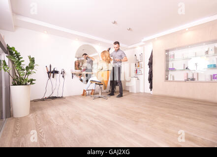 large hair salon hairdresser working woman hair. Fancy modern interior, one chair. Stock Photo