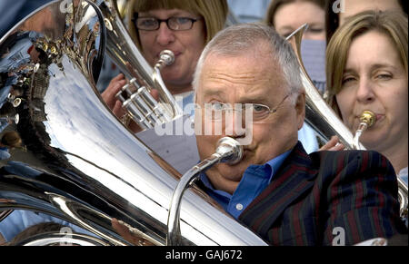 The theme tune of Australian soap Neighbours is performed by star Ian Smith (Harold Bishop), along with hundreds of brass band musicians from around the UK to celebrate its imminent arrival on Five TV, Trafalgar Square, central London. Stock Photo