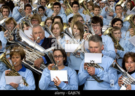 The theme tune of Australian soap Neighbours is performed by star Ian Smith (Harold Bishop), along with hundreds of brass band musicians from around the UK to celebrate its imminent arrival on Five TV, Trafalgar Square, central London. Stock Photo