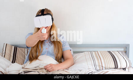 Beautiful woman using VR headset in bed Stock Photo