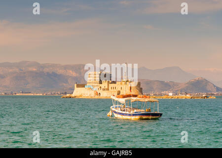 Old fishing boat against the Bourtzi castle at Nafplio in Greece. Stock Photo