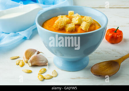 Pumpkin squash vegetable soup with garlic croutons in a blue bowl on white wooden background Stock Photo