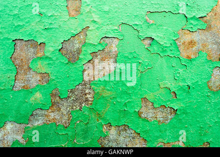 Green flaking paint falling off of a rusty metal surface with split and cracking paints holes. Stock Photo