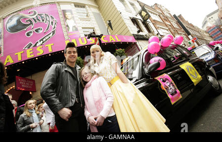 The lead roles of the musical Grease, Danny Bayne and Siobhan Dillon with Megan, aged 10 from east London, during a photocall to mark the London Taxidrivers' Fund for Underprivileged Children - who took 90 'special needs' and underprivileged children to see the musical Grease in a convoy from Bow, East London - at the Piccadilly Theatre, in central London. Stock Photo
