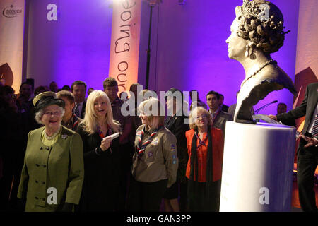 Britain's Queen looks at a bronze statue of herself created by sculptor Frances Segelman (second left) at the Scout Association Activity Centre at Baden-Powell House, London. Stock Photo