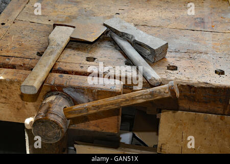 ancient tools small axe and big hammer on the old wooden workbench with a vise Stock Photo