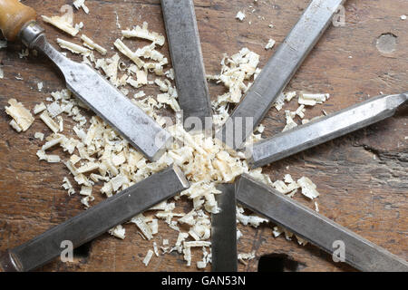 series of many sharp steel blades many chisels and sawdust chippings in Workbench Stock Photo