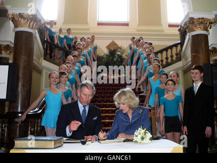 The Prince of Wales and the Duchess of Cornwall sign the visitors book watched by pupils of the Elmhurst Ballet school during a visit to reopen Birmingham's refurbished Town Hall. Stock Photo