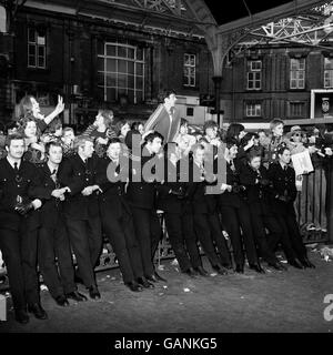 Minus helmets, policemen link arms to control some of the 500 fans of super star David Bowie on his arrival at Victoria Station.Bowie has returned home to England after two years in America, during which he starred in the film 'The Man who Fell to Earth'. Stock Photo