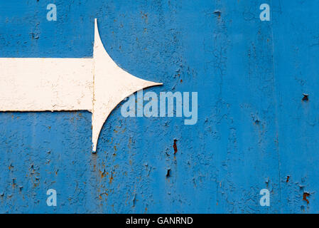 Single white metal arrowhead on a rusty dark blue metal background. Copy space area using the arrow for text and design overlays Stock Photo