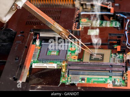 Man fixing damaged memory computer or laptop with soldering iron Stock