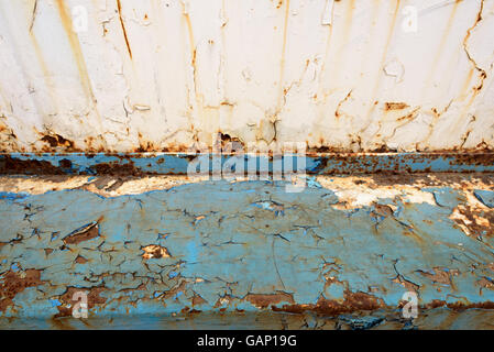 Old decrepit blue metal girder with striking unique orange colored rust sports and visible deterioration. White paint and blue Stock Photo