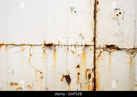 Grunge look of orange rusting metal on a painted white surface with bleeding into the paintwork Stock Photo