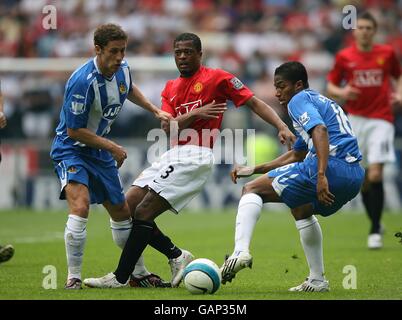 Wigan Athletic's Antonio Valencia (right) and Michael Brown (left) and Manchester United's Patrice Evra (centre) battle for the ball Stock Photo