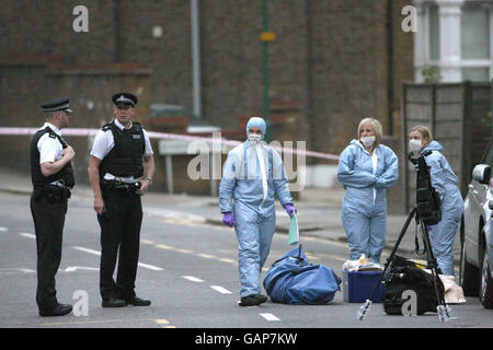 Police officers cordon off a section of Acton Lane, Harlesden, as they investigate the fatal shooting of a 30-year-old male at a barbers shop. Stock Photo