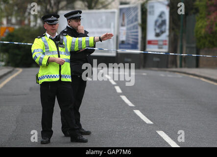 Police officers cordon off a section of Acton Lane, Harlesden, as they investigate the fatal shooting of a 30-year-old male at a barbers shop. Stock Photo