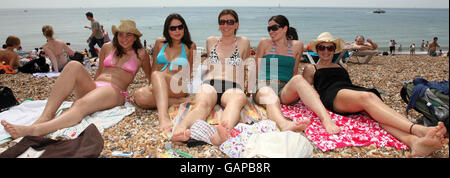 University students enjoy the hot weather on the beach at Brighton, Sussex, on what is expected to be the hottest day of the year so far. Stock Photo