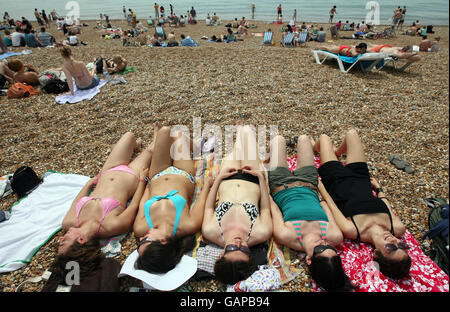 University students enjoy the hot weather on the beach at Brighton, Sussex, on what is expected to be the hottest day of the year so far. Stock Photo