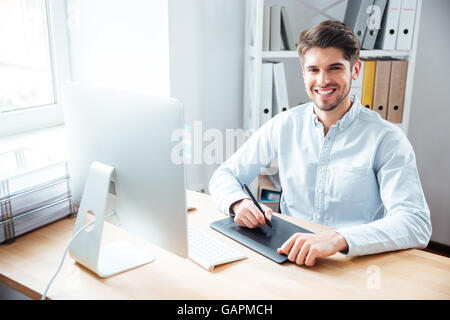 Portrait of smiling young man designer working and using graphic tablet in office Stock Photo