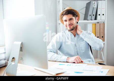 Smiling young man working with documents and computer at workplace Stock Photo
