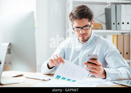 Portrait of a pensive smart businessman using mobile phone in the office Stock Photo