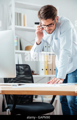 Businessman closing a deal signing documents at desk in office wearing white shirt Stock Photo