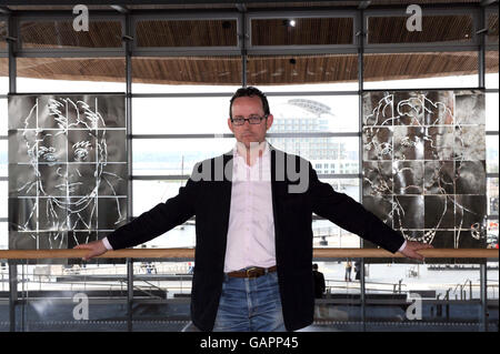 Artist Dylan Hammond at the Welsh assembly building in Cardiff in front of his portraits of Baroness Thatcher and Aneurin Bevan (left). Stock Photo