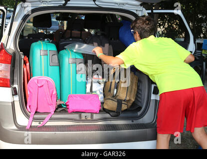 young boy loads the luggage in the trunk of the car during the trip of the summer holidays