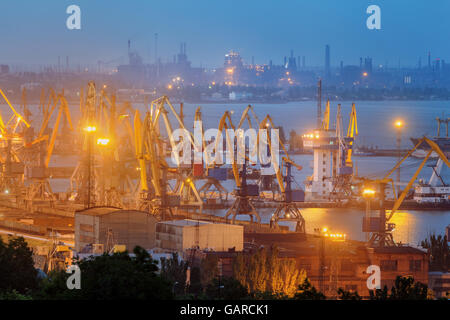 Sea commercial port at night against working steel factory in Mariupol, Ukraine. Industrial view. Cargo freight ship with workin Stock Photo