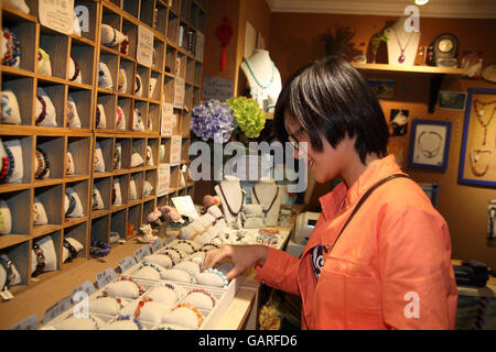 A young Chinese woman looks at bracelets in a small jewelry shop in the Tianzifang area, the Former French Quarter,. Shanghai, China. Stock Photo