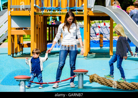 Motala, Sweden - June 21, 2016: Young adult female walking with a young boy at the playground. Possibly mother and son. Girl wal Stock Photo