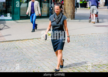 Motala, Sweden - June 21, 2016: Woman in skirt and blouse walking at a street in town. She also wears a scarf and ballerina shoe Stock Photo